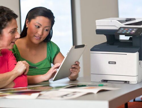 Zwei Frauen nutzen ein Tablet vor einem Xerox® VersaLink® B415 Multifunktionsdrucker